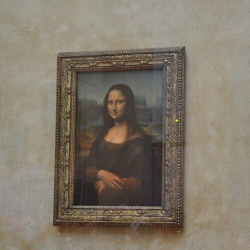 Leonardo da Vinci's Mona Lisa painting displayed alone in the Louvre Museum, protected by climate-controlled bulletproof glass.