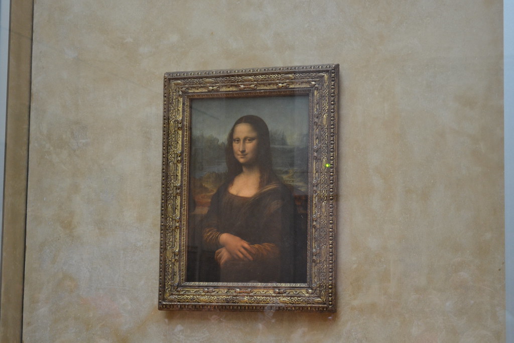 Leonardo da Vinci's Mona Lisa painting displayed alone in the Louvre Museum, protected by climate-controlled bulletproof glass.