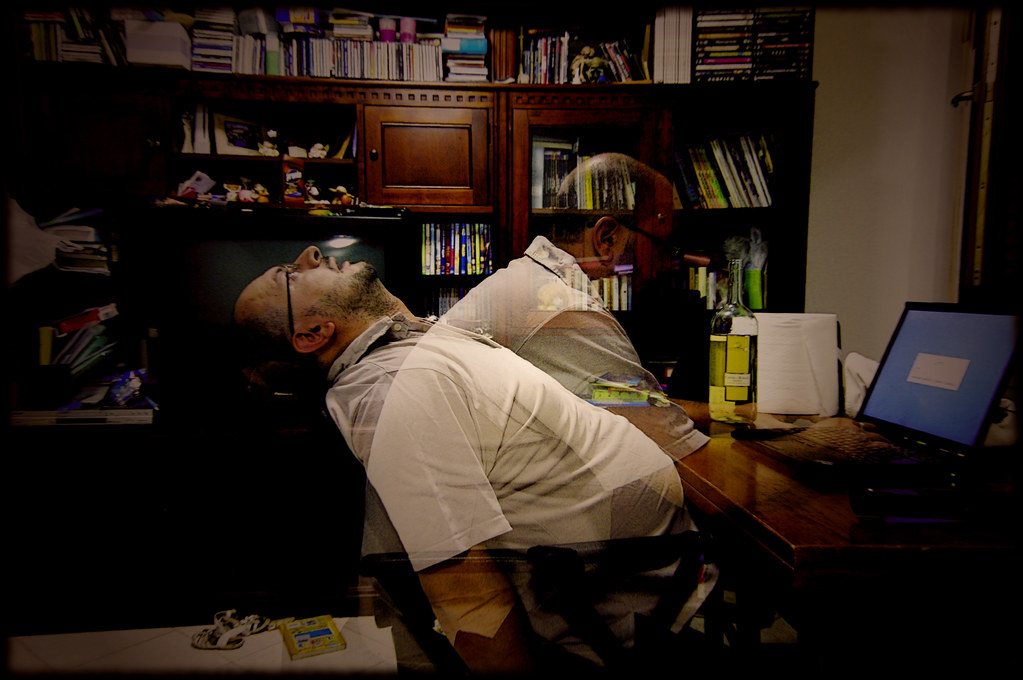 A tired man slumped at a desk with a blurred double exposure effect, symbolizing burnout and overwhelm—highlighting the importance of daily habits to reduce stress and reclaim balance.